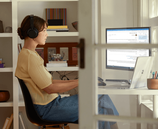 A person typing on a laptop perched on a cube sending an email